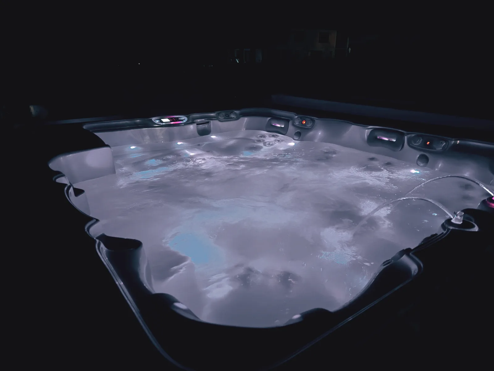 Jacuzzi luminat noaptea, cu apa strălucind în întuneric